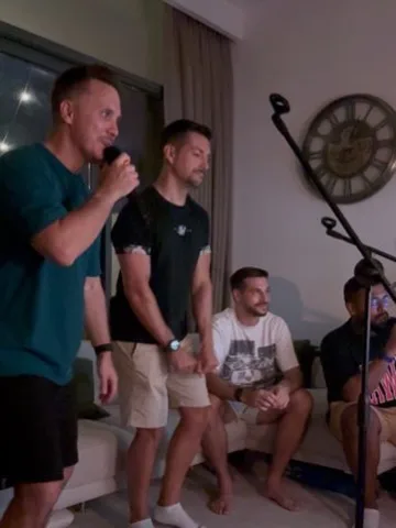 Guest singing while friends watch from the sofa
