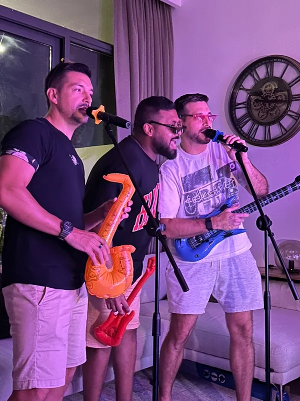 Three friends singing with an inflatable saxophone and guitar